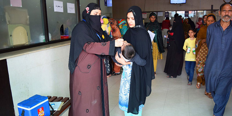 Aliya administering polio drops to child during