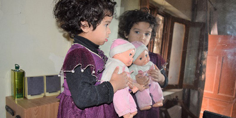 Rijha and her doll posing in front of a mirror