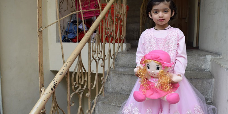 Toddler Jannat playing with her doll after vaccination